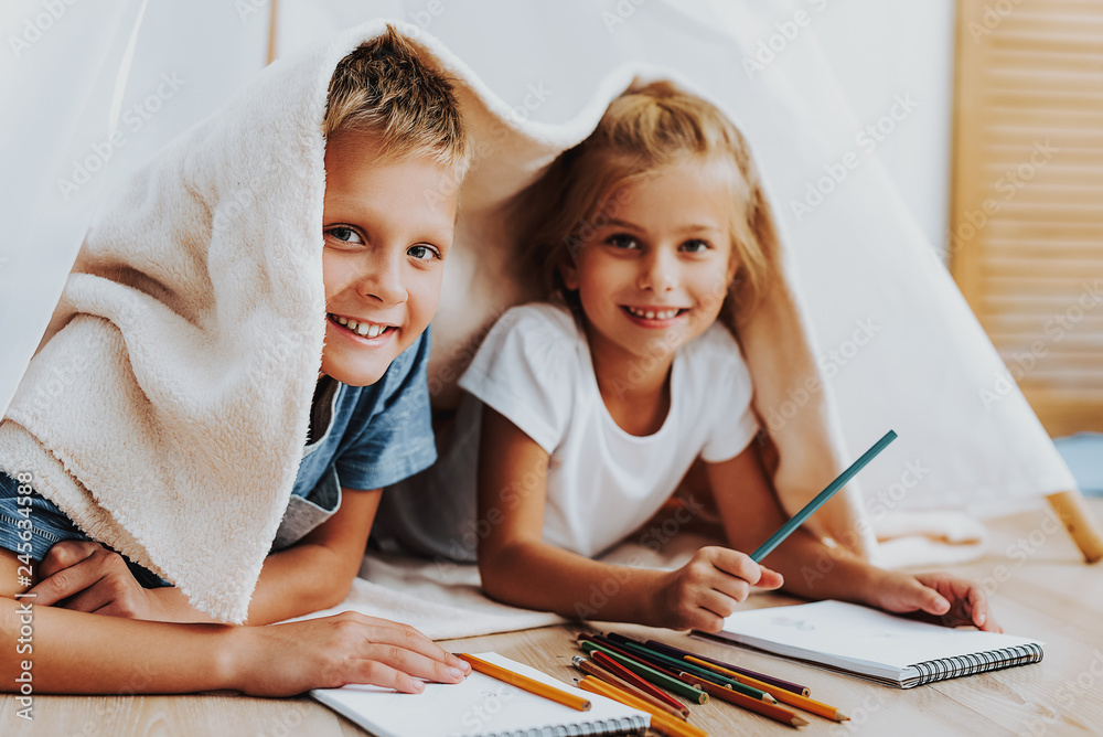Happy kids drawing together covering by blanket Happy kids drawing together covering by blanket