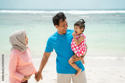 father, mother, and his daughter together walking and relaxing around the beach