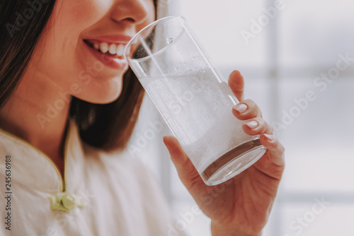 Smiling young girl holding glass with water and medicament