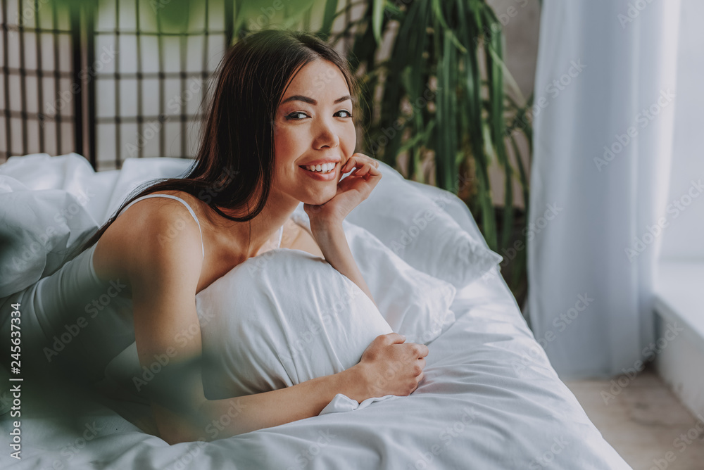 Charming asian woman looking at camera on bed