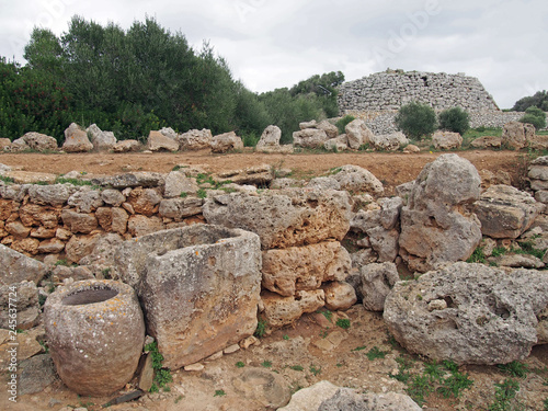 ancient stone walls and ancient objects in trepuco minorca with talayot and enclosure in the distance