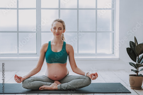 Fototapeta Naklejka Na Ścianę i Meble -  Beautiful young pregnant woman meditating on sport mat