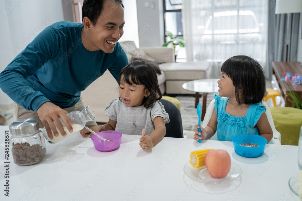 father pouring milk in to the bowl for his children