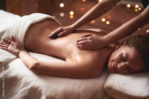Foto Smiling lady having massage with warm stones