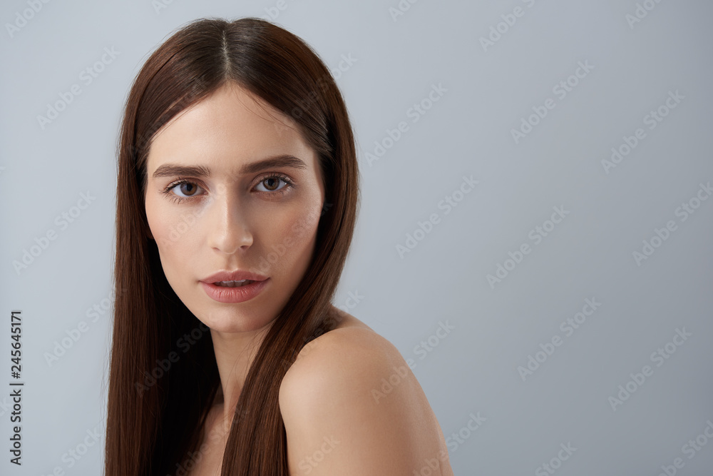 Beautiful girl with natural makeup standing against light blue background Beautiful girl with natural makeup standing against light blue background