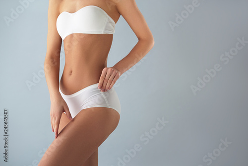Young woman in white lingerie standing against light blue background