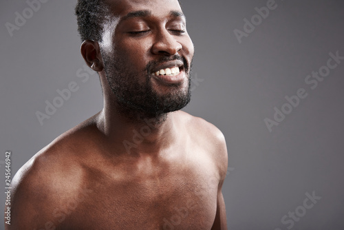 Close up of a delighted afro American man standing against gray background