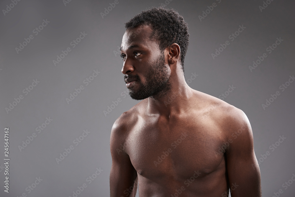 Waist up of a pleasant afro American man looking aside