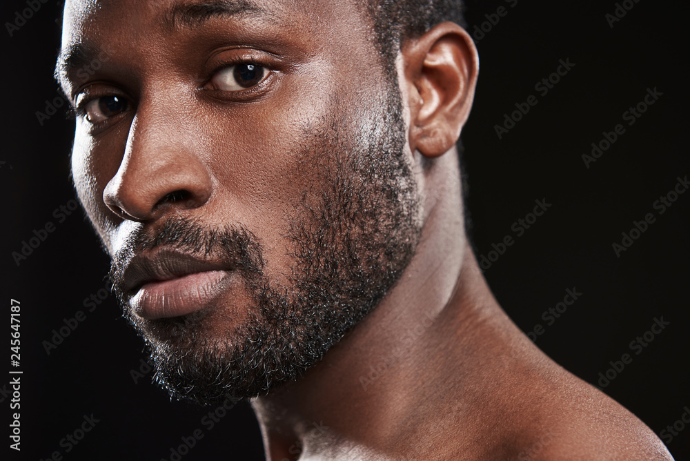 Facial expression of a smiling afro American man against black background