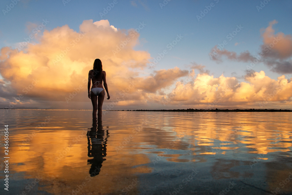Silhouetted woman standing in a water at sunset on Taveuni Island, Fij