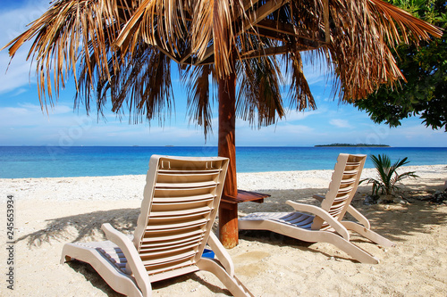 Sun chairs with thatched umbrella on a white sandy beach photo