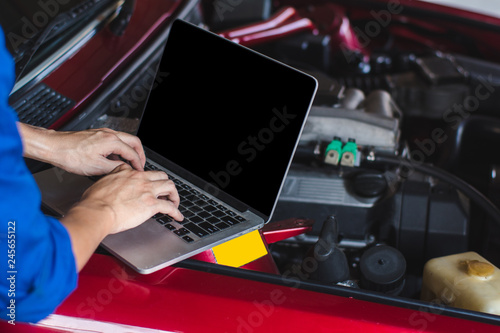 Professional mechanic working in auto repair service,with laptop