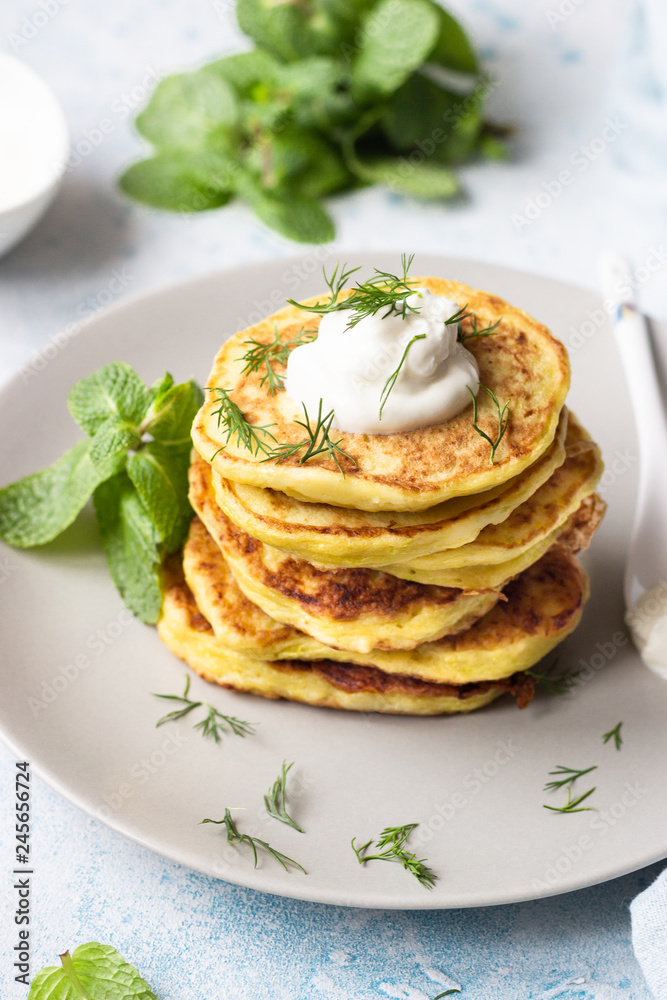 Zucchini fritters served with fresh herbs and yogurt dressing. Vegetarian zucchini pancakes. Copy space.