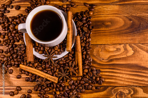 Cup of hot coffee, star anise, cinnamon sticks and scattered coffee beans on wooden table. Top view © ihorbondarenko