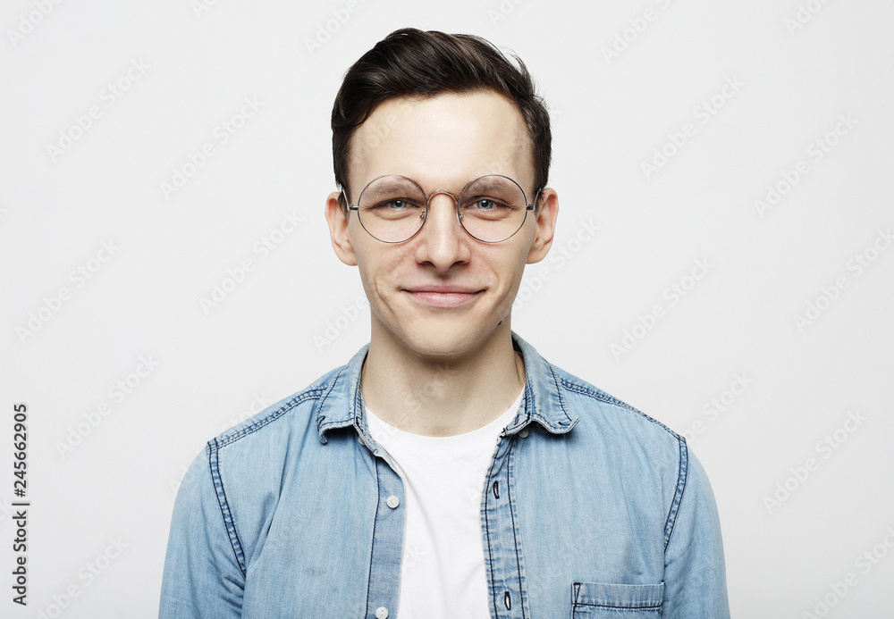 Portrait of a smart young man wearing eyeglasses standing against white background