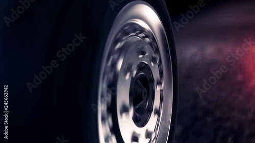 Side view of abstract car wheel driving back on black road. Close up for car wheel with silver disc moving back on abstract black asphalt road.