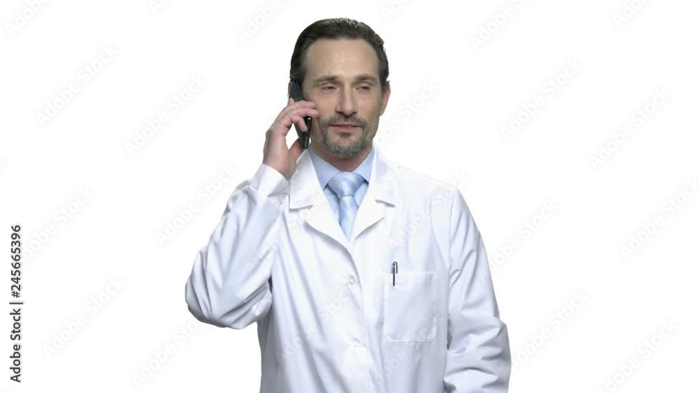 Friendly man in white coat talking on phone. Attractive mature doctor or lab technician talking on cell phone over white background. Friendly man in white coat talking on phone. Attractive mature doctor or lab technician talking on cell phone over white background.