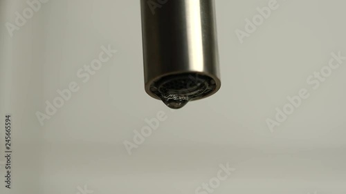 MACRO: Dripping faucet on a white background - Slow motion