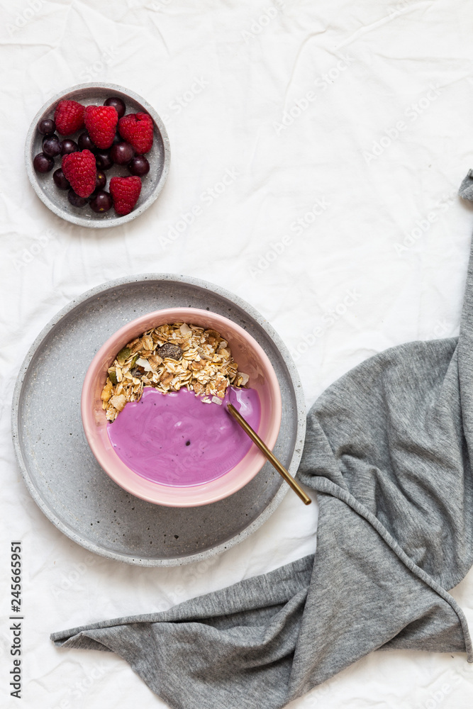 Bowl of oat granola with yogurt, fresh raspberries, cranberries