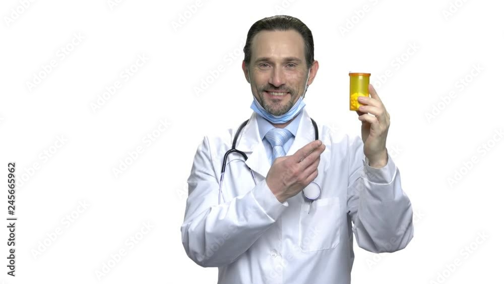 Happy mature doctor showing bottle of pills. Smiling male physician holding orange bottle with pills and pointing on it with finger. People, midicine and health care concept. Happy mature doctor showing bottle of pills. Smiling male physician holding orange bottle with pills and pointing on it with finger. People, midicine and health care concept.