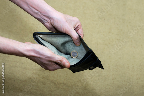 hands hold open wallet in which only one coin