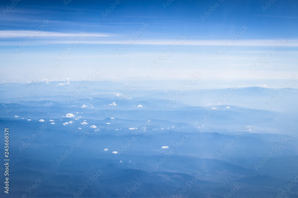 clouds and blue sky with mountain background, view from window of airplane