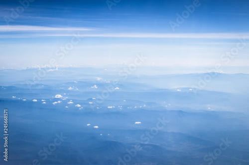 clouds and blue sky with mountain background, view from window of airplane