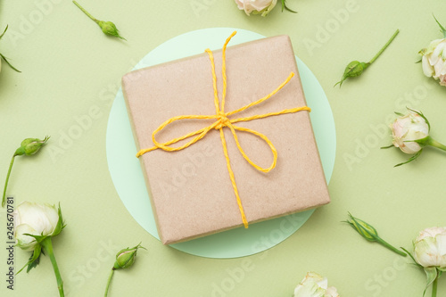 Holiday present. Craft paper gift box. Minimal rose decor on green background.