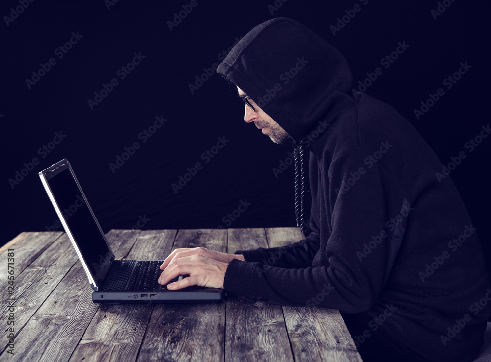 hacker in black hoody with laptop hacker in black hoody with laptop