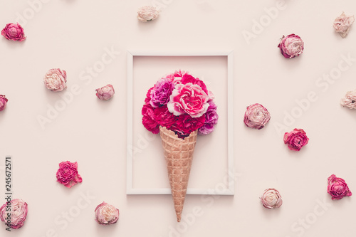 Conceptual flower gift composition. Carnation in cream cone arranged in frame. Rose heads on ivory background.