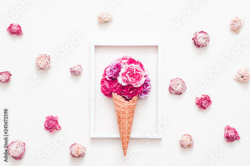 Conceptual art. Flower gift composition. Dark pink carnation in cream cone. Photo frame and roses on white background.