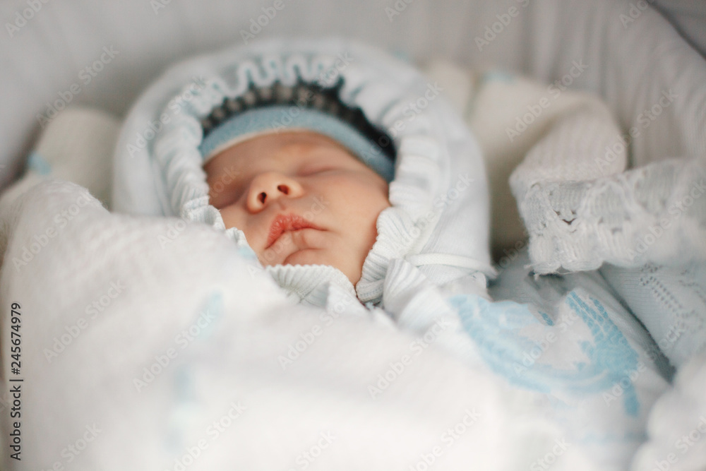 Little baby is lying in a stroller on the street and sleeping sweetly. Close-up.