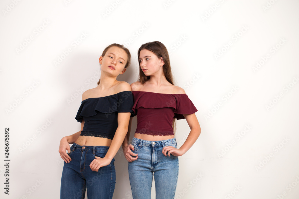 Two young girlfriends posing against wall Two young girlfriends posing against wall