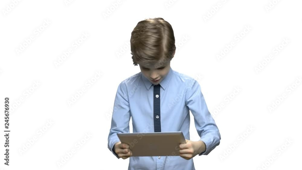 Preteen boy playing game on tablet pc. Enthusiastic child boy plays game on computer tablet over white background. Digital gadget addiction. Preteen boy playing game on tablet pc. Enthusiastic child boy plays game on computer tablet over white background. Digital gadget addiction.