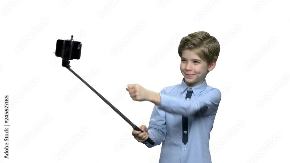 Boy with monopod showing fig to camera. Attractive caucasian child boy in blue shirt posing for camera over white background. Boy with monopod showing fig to camera. Attractive caucasian child boy in blue shirt posing for camera over white background.
