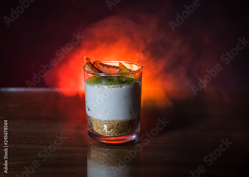 Sweet cheesecake in glass on a table with toned foggy backglight. photo