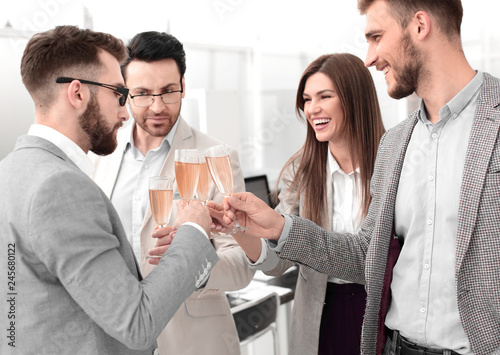 business team raises glasses of champagne in the office © ASDF