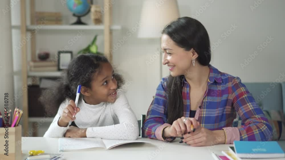 Caucasian teacher is helping to mixed-race girl in school. Encouraging support on working hard and good learning in classroom. Cheerful pupil smile and laugh getting knowledge together with tutor. Caucasian teacher is helping to mixed-race girl in school. Encouraging support on working hard and good learning in classroom. Cheerful pupil smile and laugh getting knowledge together with tutor.
