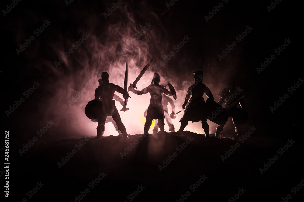 Medieval battle scene. Silhouettes of figures as separate objects, fight between warriors on dark toned foggy background. Night scene. Medieval battle scene. Silhouettes of figures as separate objects, fight between warriors on dark toned foggy background. Night scene.