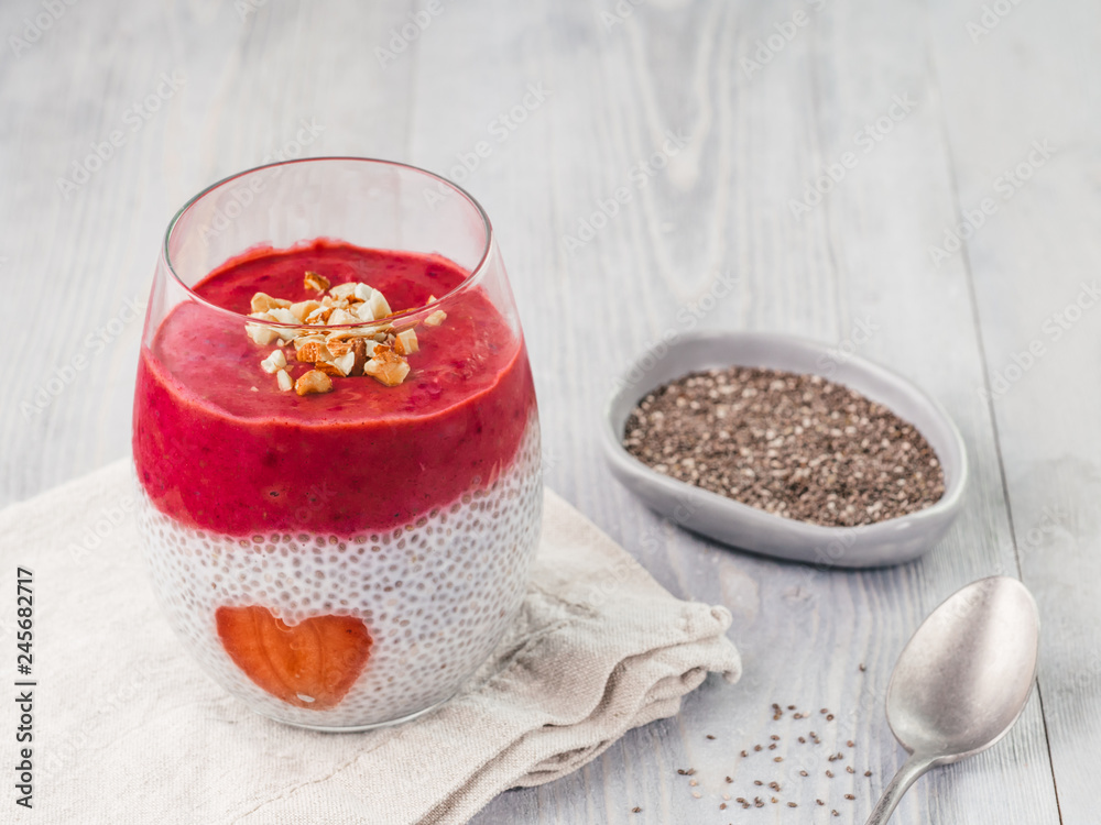 Naklejka premium Idea for healthy breakfast on Valentine's Day: Chia pudding with red berry puree, chopped almonds on top and strawberry in the shape of heart. Copy space for text