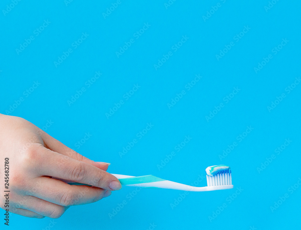 Toothpaste on a toothbrush close-up on a blue light background Toothpaste on a toothbrush close-up on a blue light background
