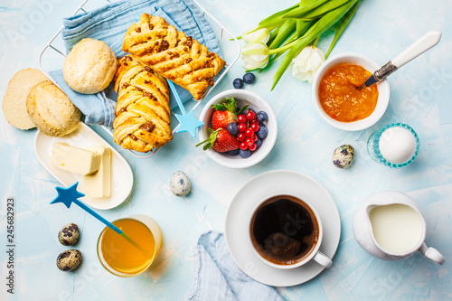 Breakfast table. Coffee, eggs, buns, juice and jam. Blue background, top view, food flat lay.