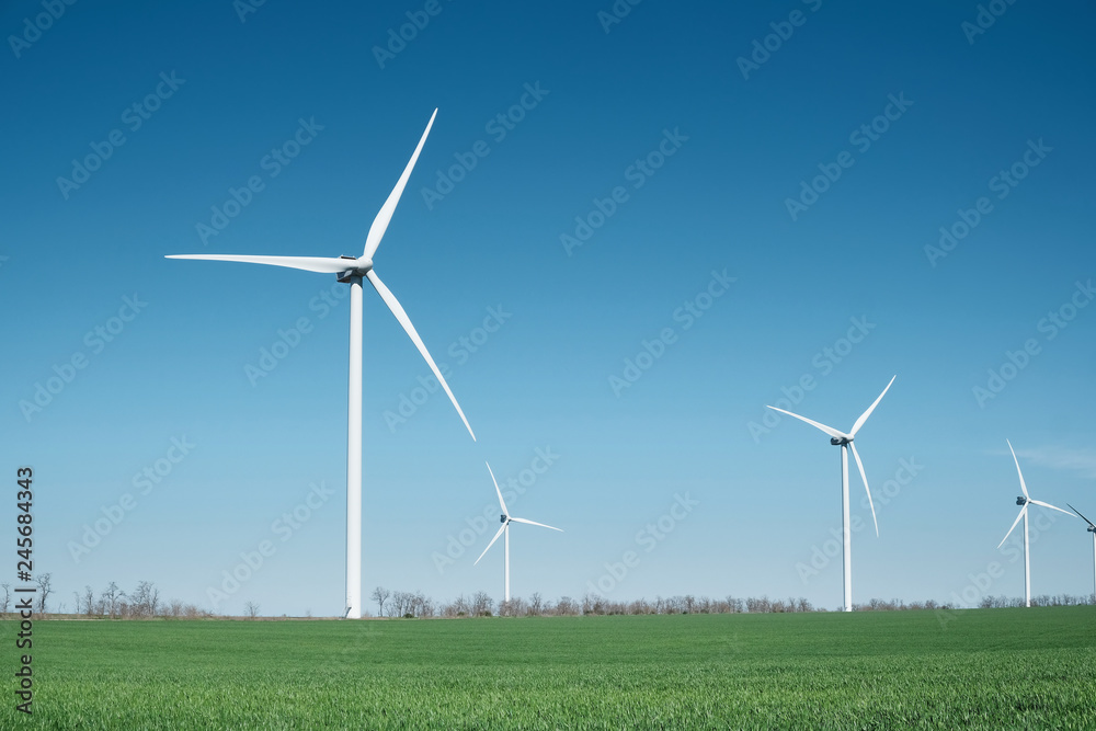 Wind power station on field. Technology and inovation. Green energy composition. Wind turbines. Industrial landscape Wind power station on field. Technology and inovation. Green energy composition. Wind turbines. Industrial landscape