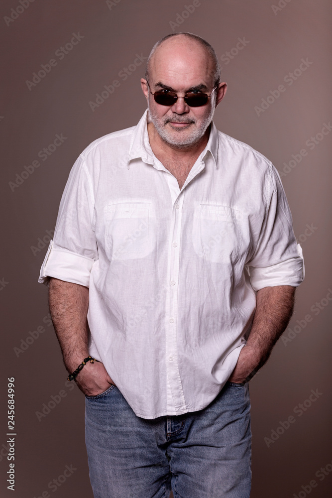 Brutal bald elderly man in shirt, jeans and sunglasses Brutal bald elderly man in shirt, jeans and sunglasses