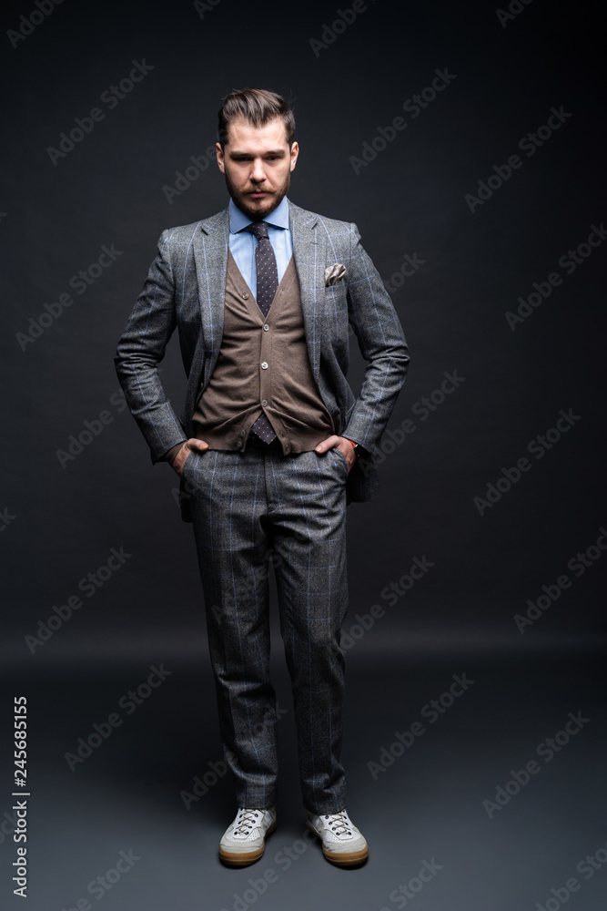 Full length portrait of a fashion male model over black background. Looking at camera.