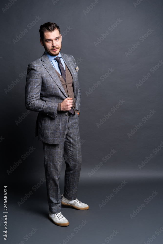 Full length portrait of a fashion male model over grey background. Looking at camera. Full length portrait of a fashion male model over grey background. Looking at camera.