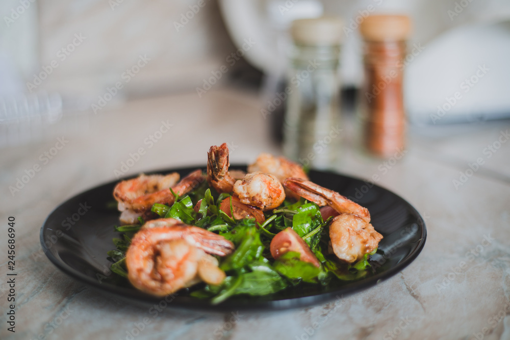 salad with shrimps and tomatoes on a black plate salad with shrimps and tomatoes on a black plate