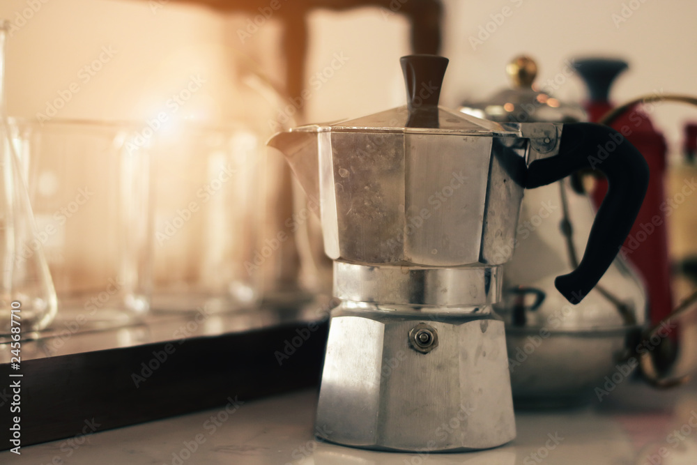 dirty white aluminum italian moka coffee pot on a wood table, closeup dirty white aluminum italian moka coffee pot on a wood table, closeup