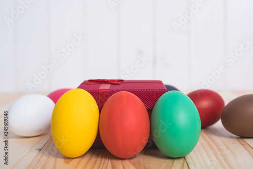 Easter eggs clean around red box gift on wooden background