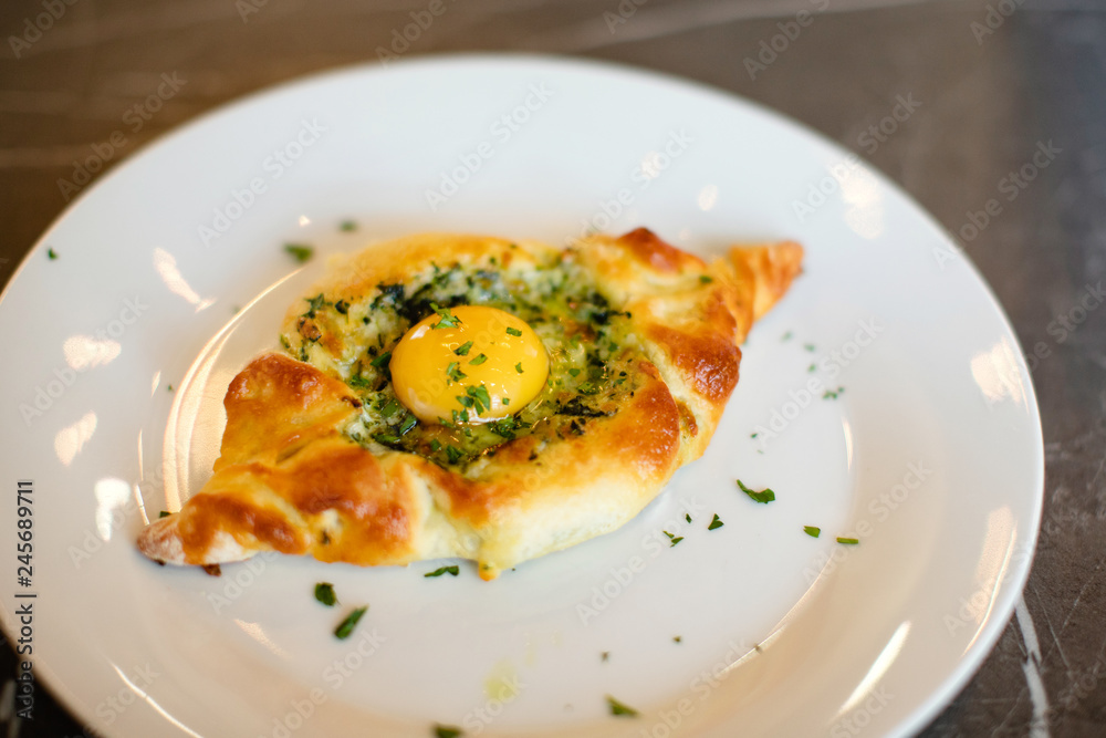 Georgia adjarian Khachapuri with spinach, cheese and yolk filling on plate Georgia adjarian Khachapuri with spinach, cheese and yolk filling on plate